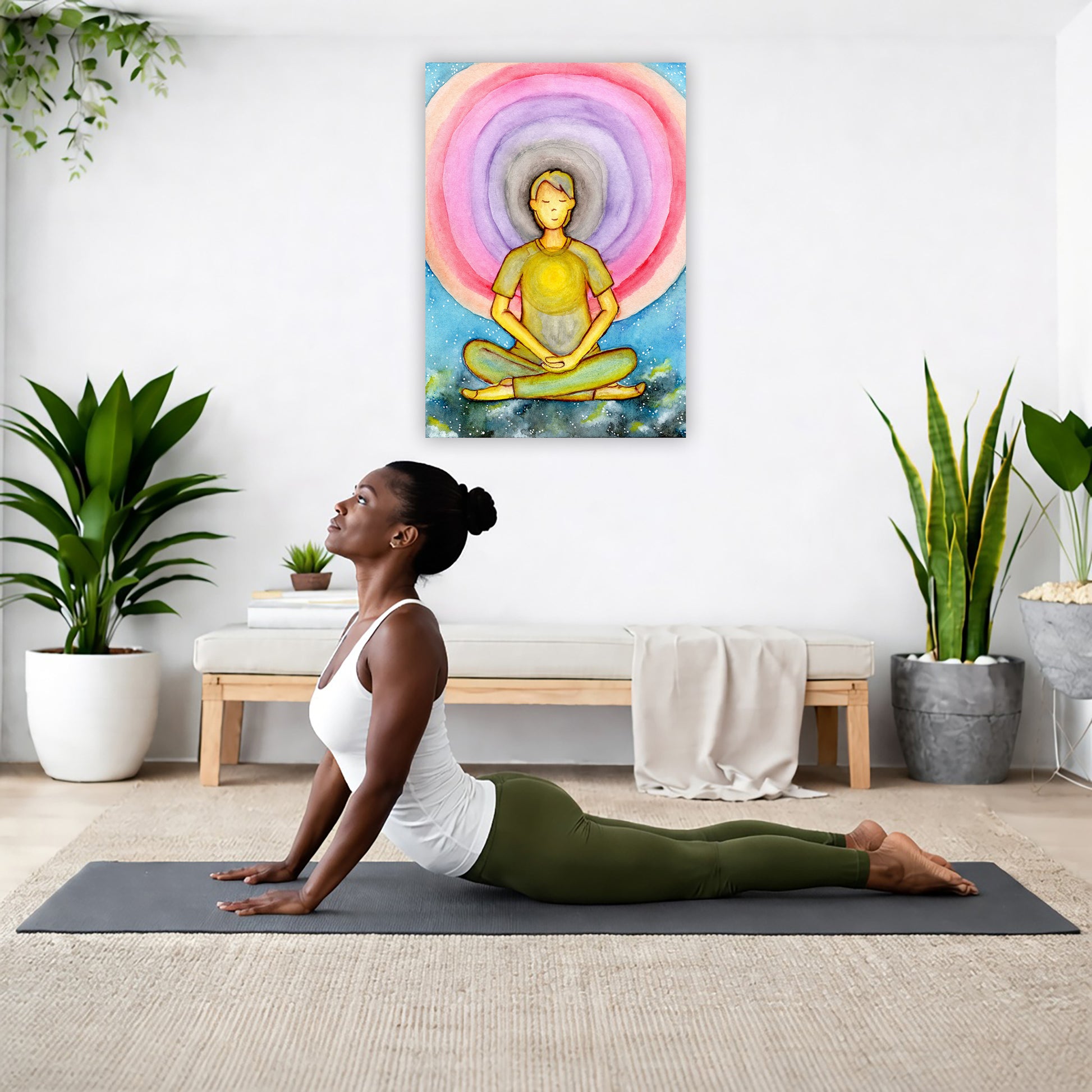 Canvas of a young man's heart chakra glowing and aura energy flowing around him. This is a print of the original hand-painted watercolor by Brazilian artist Thaís Suizo for the LET'S MEDITATE SERIES of mediation guides.  The poster is hanging on the wall. A woman on her yoga mat is doing the cobra pose in front of the poster. There is a potted plant and a hanging plant on the left side. A padded bench with material draped over it is behind her. On the right side are two potted plants.
