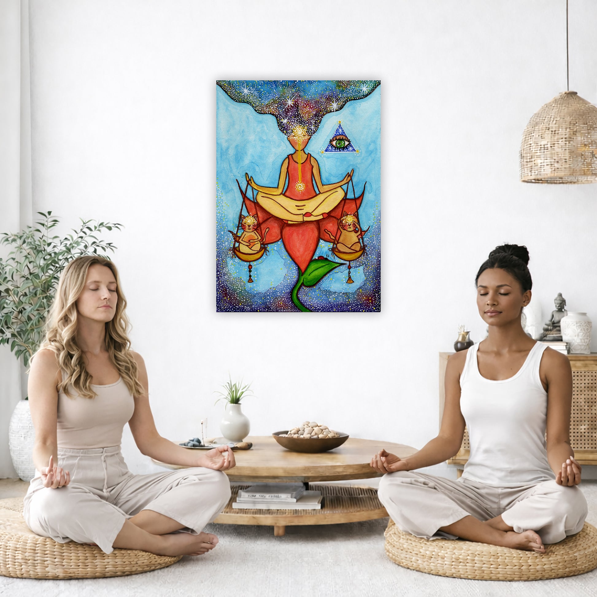 Poster of a woman meditating on a lotus with a glowing third eye and holding scales balancing two cats. This is a thumbnail of the original hand-painted watercolor by Brazilian artist Thaís Suizo for the LET'S MEDITATE SERIES of mediation guides.  The poster is in the center of the living room wall. Two women are sitting on wicker pillows meditating. Behind them is a small round coffee table with incense, a green potted plant and a bowl of shells. There is a potted plant to the left and a Buddha statue and 