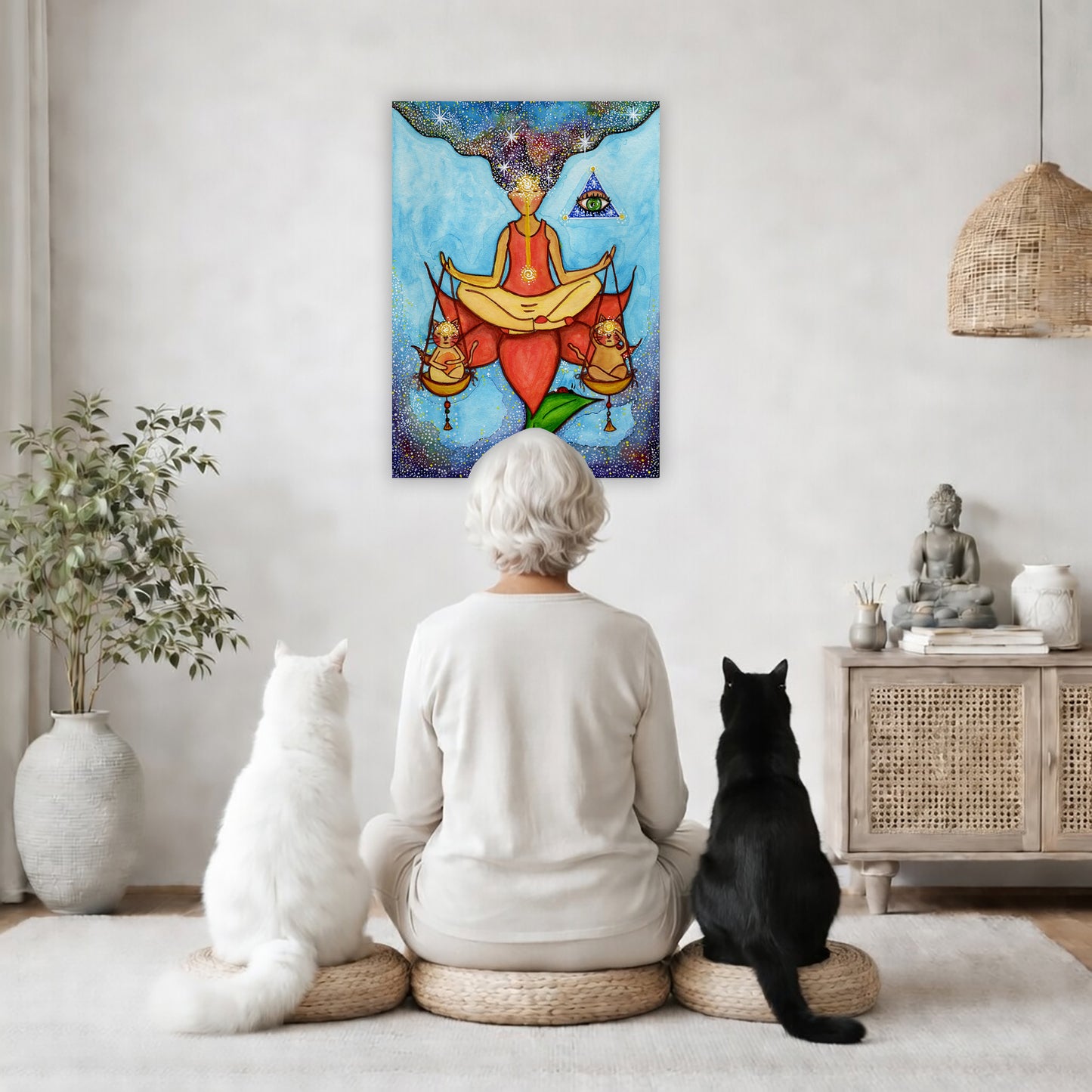 Poster of a woman meditating on a lotus with a glowing third eye and holding scales balancing two cats. This is a thumbnail of the original hand-painted watercolor by Brazilian artist Thaís Suizo for the LET'S MEDITATE SERIES of mediation guides. The poster is in the center of the living room wall. A woman is meditating facing the poster with a white cat on her left side and a black cat on her right side. There is a potted plant on the left side and a cabinet with a Buddha statue on it on the right side. 
