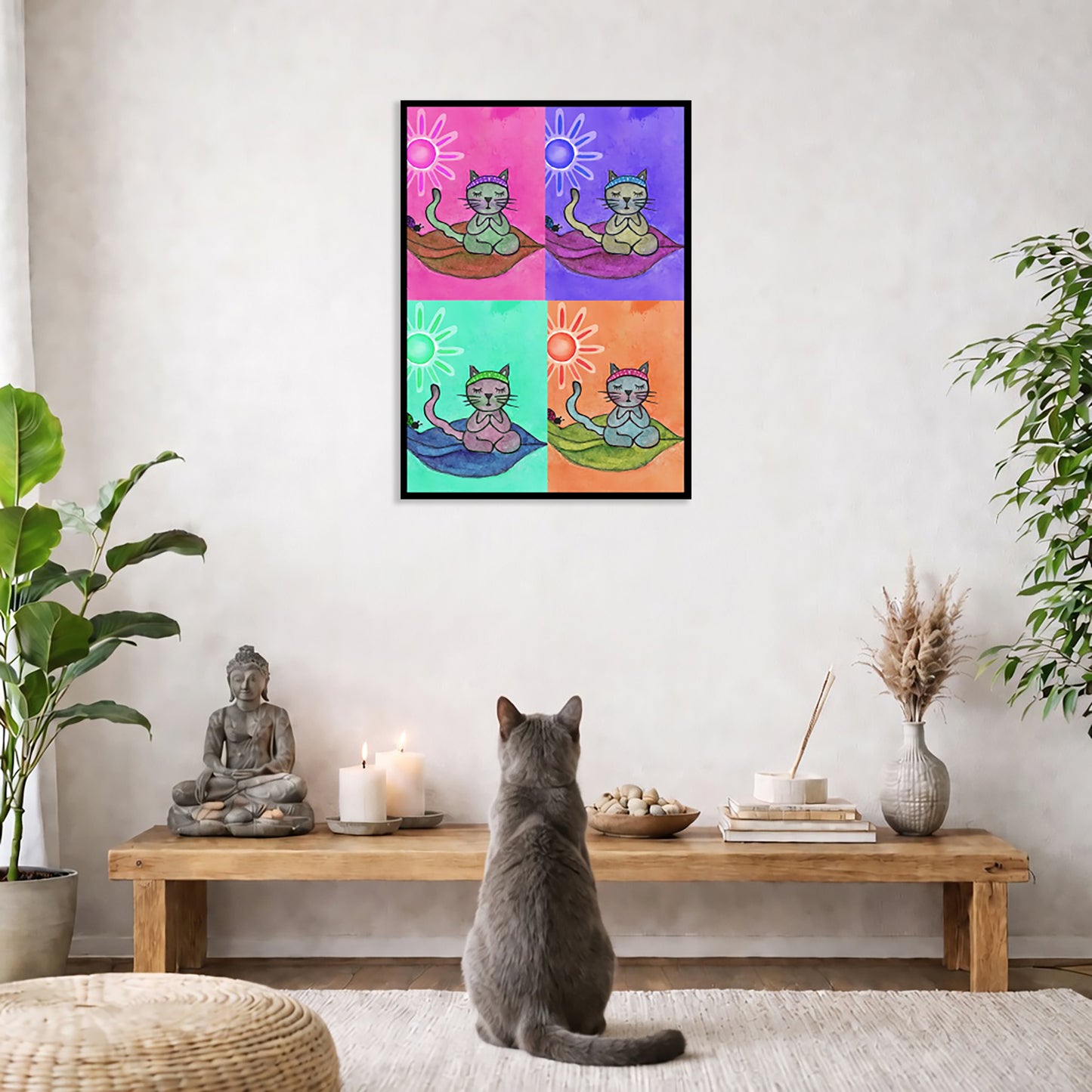 Multi colored grid of four cats meditating on a leaf framed poster. This is a print of the original hand-painted watercolor by Brazilian artist Thaís Suizo.   The poster is in the center of the living room wall. A gray cat is facing the poster. In front of it is a coffee table with a Buddha statue and burning candle on the left and incense and an orange cat staring at the poster on the right. There is a green potted plant on both the left and right side of the coffee table.