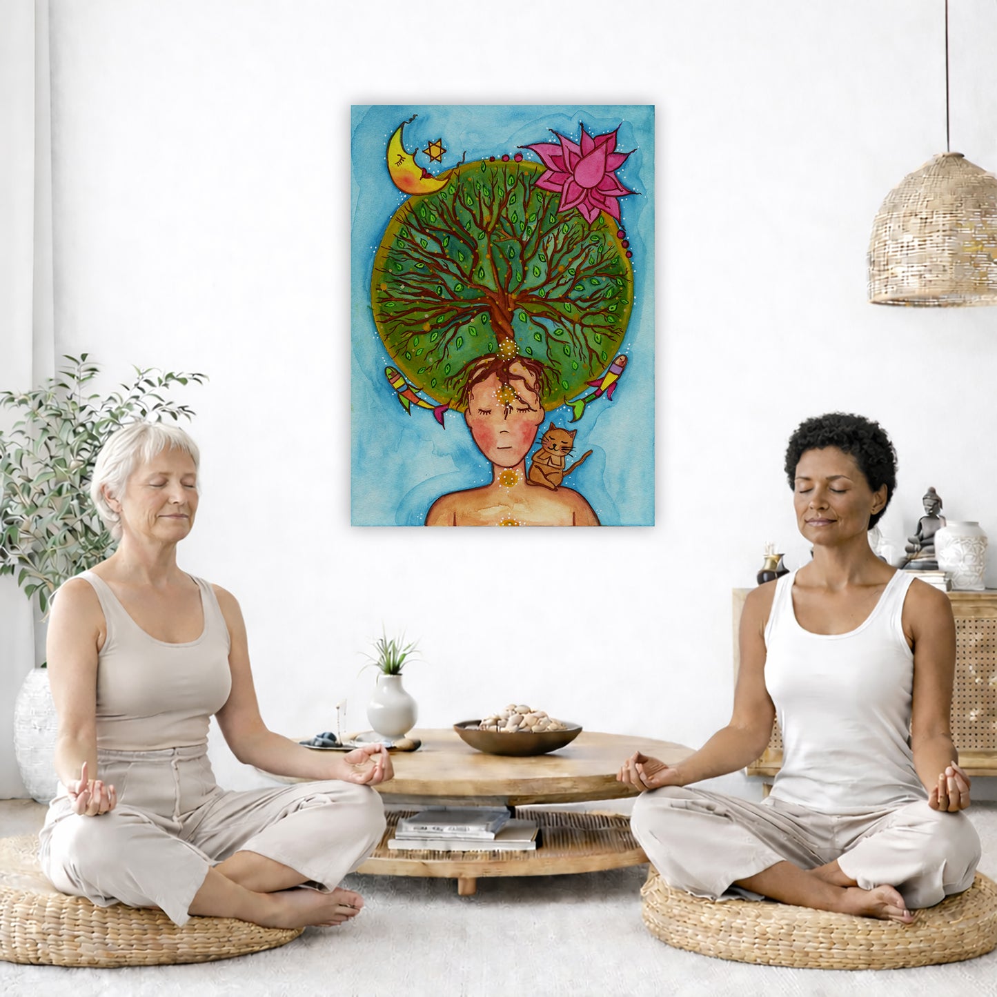 canvas of a woman meditating with her crown chakra blooming into the tree of life. Her cat is sitting on her shoulder. The poster is in the center of the living room wall. Two women are sitting on a giant pillow having a coffee. Beside them is a small tray with a pot of coffee and incense. To the left is a green floor plant and a hanging green plant. To the right of them is a green floor plant.