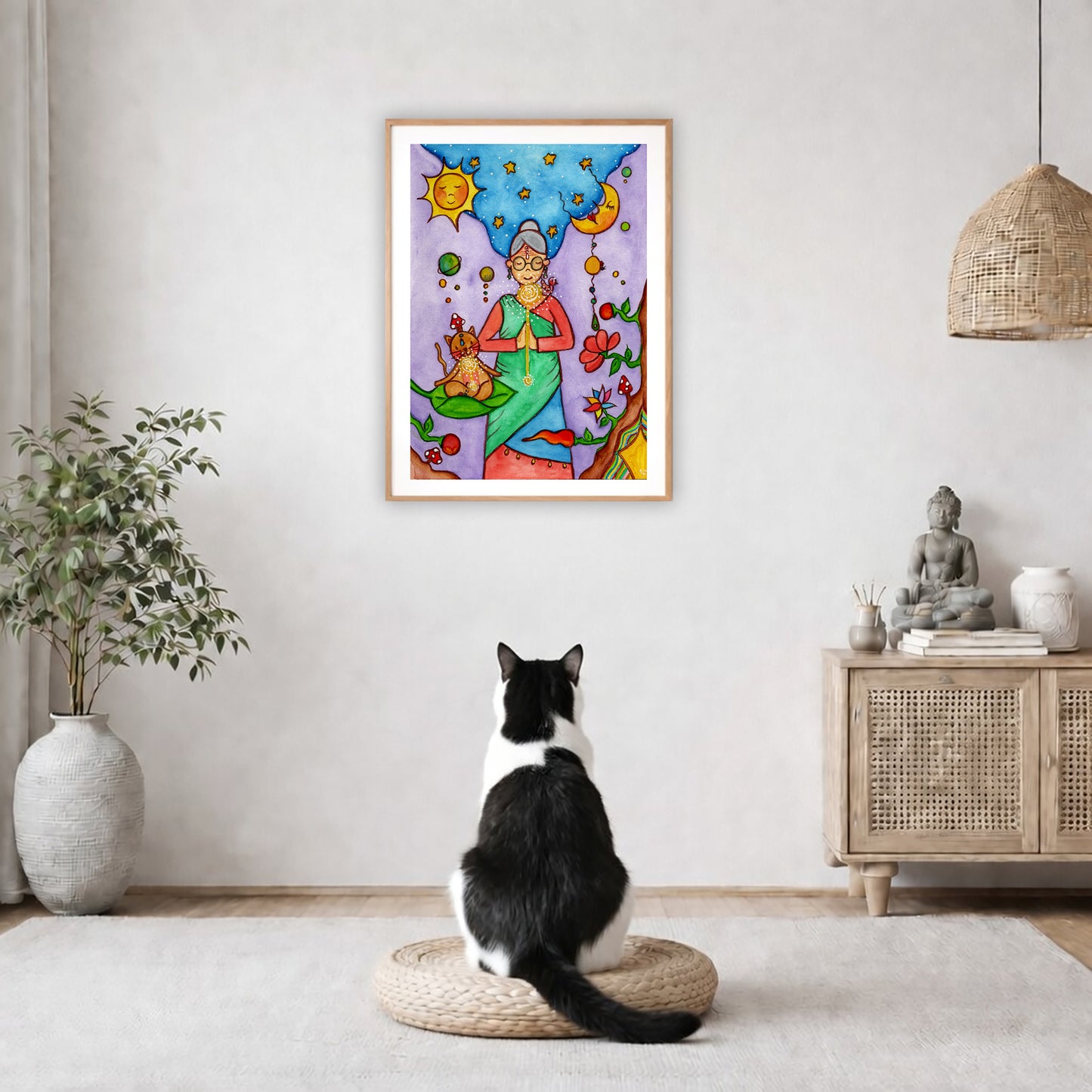Poster of a woman's throat chakra energy glowing.  The poster is framed and is in the center of the living room wall. A black and white cat is staring at the poster. There is a potted plant on the left side and a cabinet with a Buddha statue on it on the right side. 

