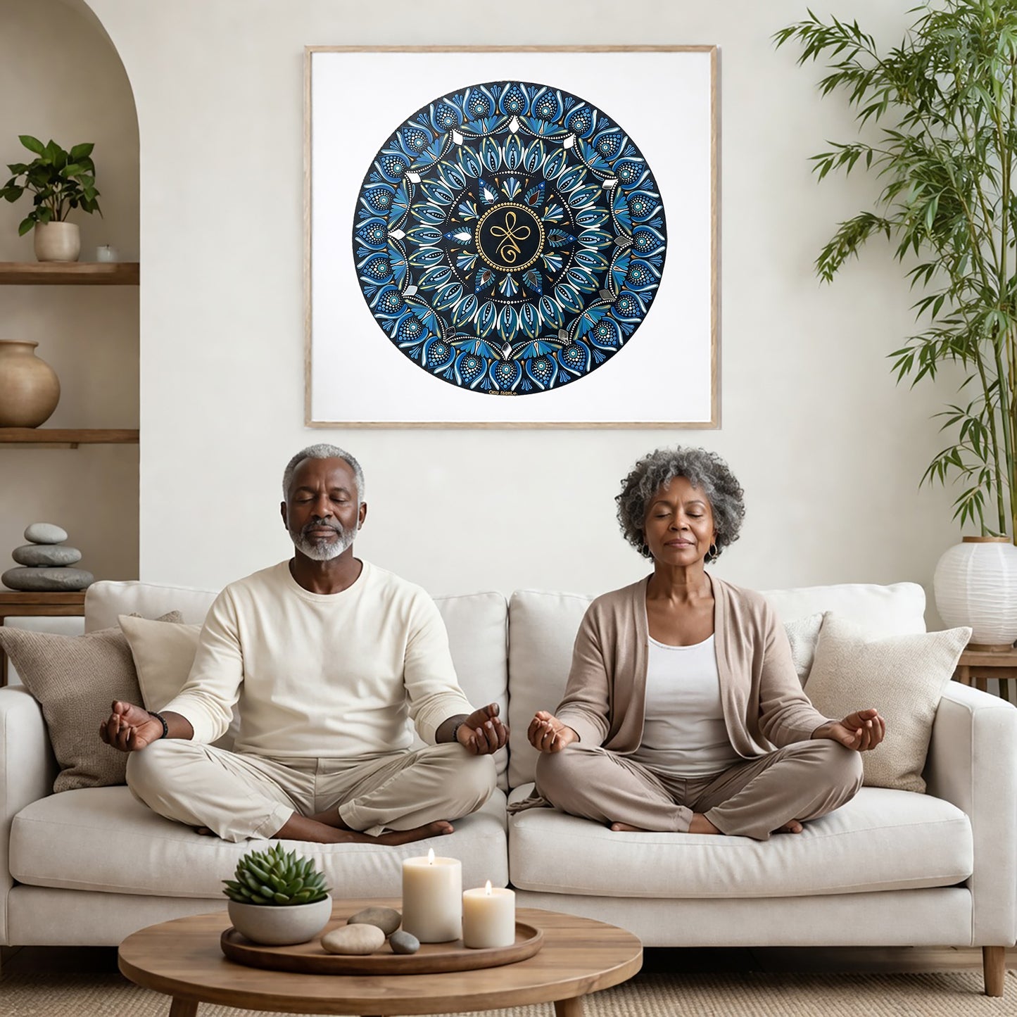 Mandala featuring three looping shapes in the center with layered symmetrical patterns, detailed meditation design on a mindfulness poster.  A couple is meditating on their couch. The mandala is framed on a wall behind them. There is a coffee table in front with candles burning and a potted plant. There is a potted plant to the right and shelves on the left.
