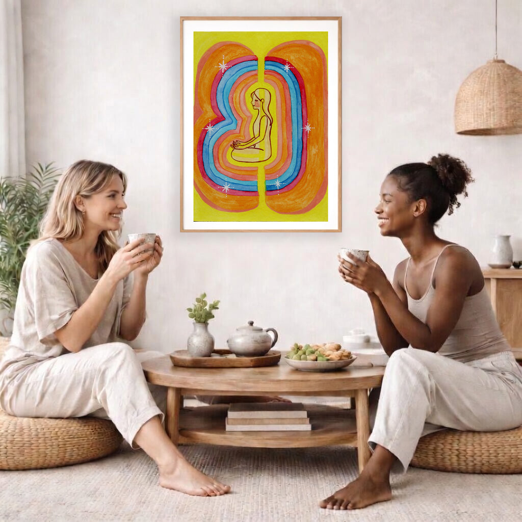 This poster showcases the beautiful, layered colors of the human aura.  The poster is framed and is in the center of the living room wall. Two female friends are having tea, grapes and cookies on a coffee table in front of the poster. On the left there is a green potted plant and to the right there is a hanging lamp.
