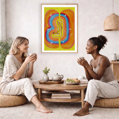 This poster showcases the beautiful, layered colors of the human aura.  The poster is framed and is in the center of the living room wall. Two female friends are having tea, grapes and cookies on a coffee table in front of the poster. On the left there is a green potted plant and to the right there is a hanging lamp.
