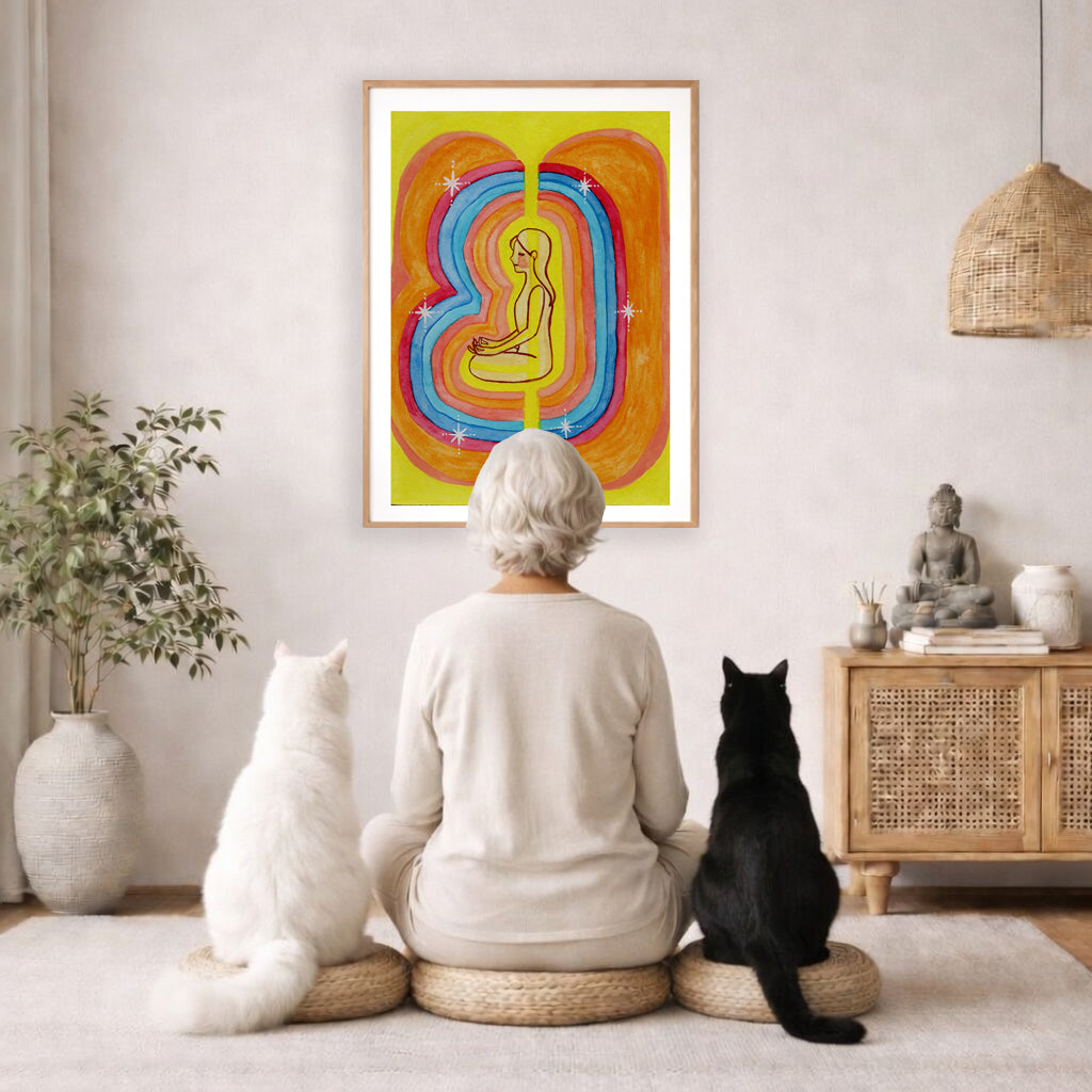 This poster showcases the beautiful, layered colors of the human aura. The poster is framed and is in the center of the living room wall. A woman is meditating facing the poster with a white cat on her left side and a black cat on her right side. There is a potted plant on the left side and a cabinet with a Buddha statue on it on the right side. 