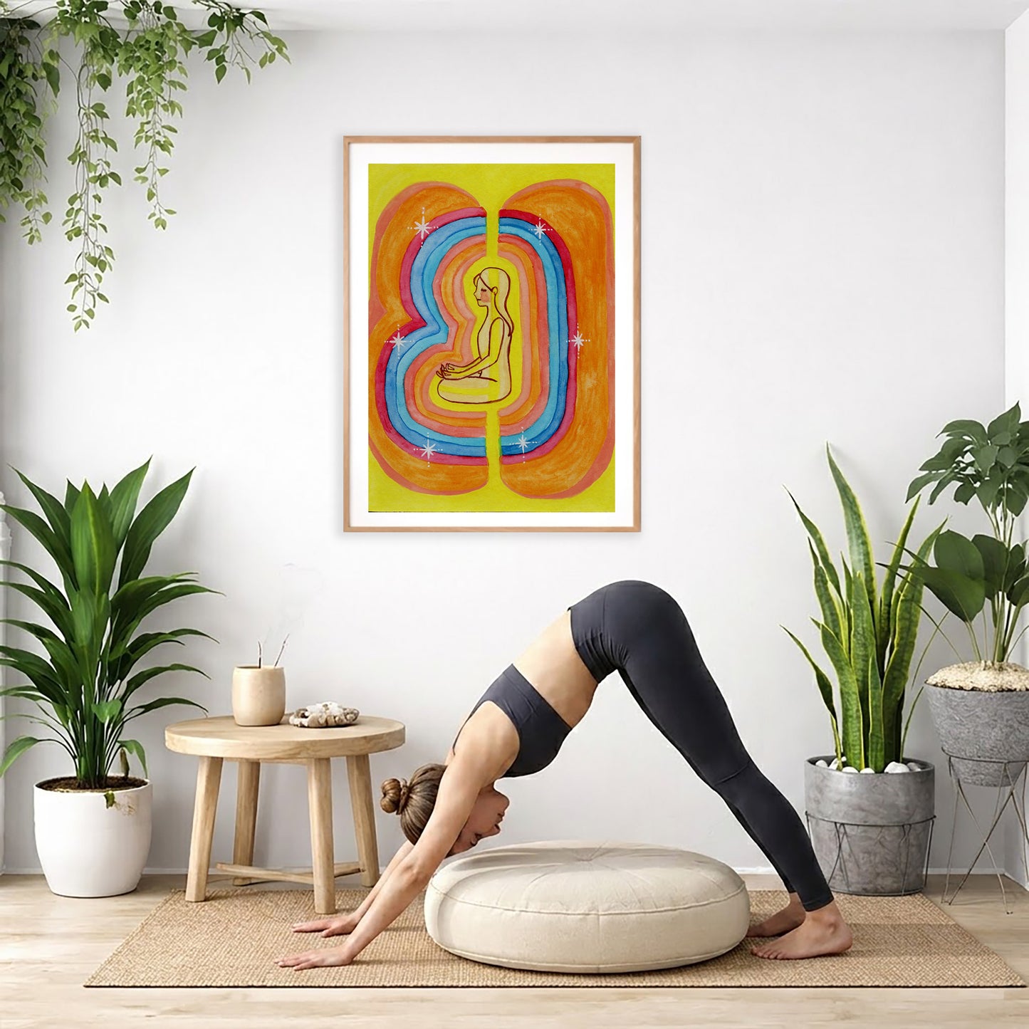 This poster showcases the beautiful, layered colors of the human aura.  The poster is framed and is in the center of the living room wall. Below the poster a woman is doing the yoga posture downward facing dog on a wicker yoga mat.
