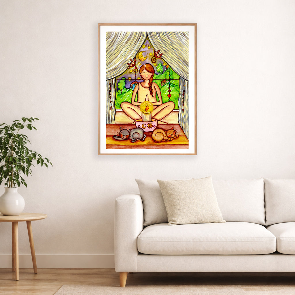 Candlelight trataka meditation design on mindfulness poster. The poster is framed and is in the center of the living room wall. Below the poster is a white couch and a hardwood floor. To the bottom left there is a green potted plant on a small table.
 