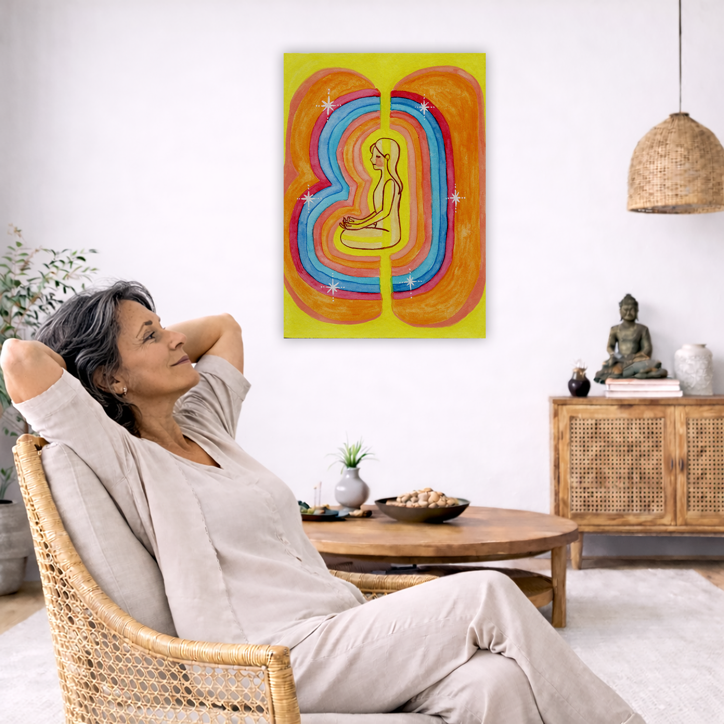 Rainbow aura energy field portrait on mindfulness canvas poster.  The poster is framed and is in the center of the living room wall. To the left a woman is relaxing in her chair with her hands behind her head. There is a small coffee table beside her with a bowl of walnuts, incense and a small green plant. On the right side of the room is a cabinet with a Buddha statue, books and an urn on it. To the left is a green floor plant.
