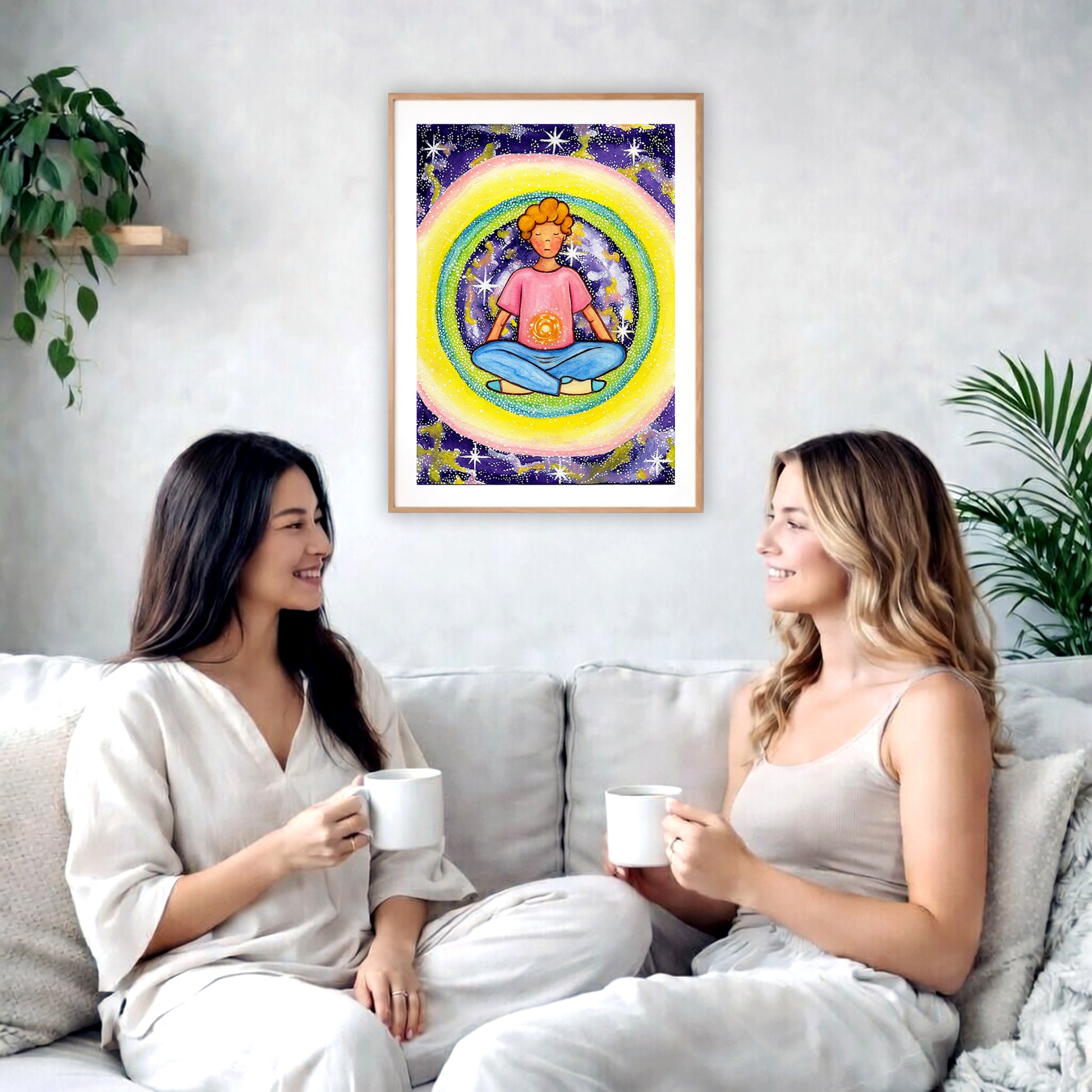 Poster of a young man meditating with his solar plexus glowing. Surrounding him is his colorful aura.  The poster is in the center of the living room wall. Two female friends are sitting on a white couch having tea. On the left and rights sides there is a green potted plant.