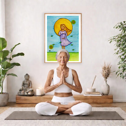 Woman standing in meditation under a glowing sun with blue sky background, calming watercolor spiritual illustration.  The poster is framed and is in the center of the living room wall. There is a woman meditating facing away from the wall. Behind her is a coffee table with incense and a Buddha statue. There are potted plants on the right and left side of the background.
