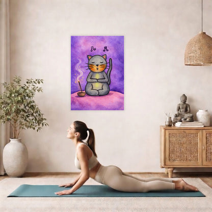 Poster of a gray cat chanting while sitting on a pink cloud. Whimsical spiritual meditation illustration.  The poster is hanging on the wall. A woman on her yoga mat is doing the cobra pose in front of the poster. here is a potted plant on the left side and a cabinet with a Buddha statue on it on the right side.
