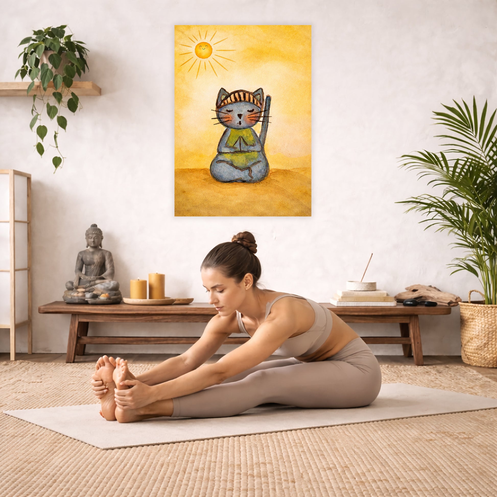 Poster of a gray cat meditating peacefully on a sunny day with warm light and calm surroundings.  The poster is hanging in the middle of the living room wall. A woman is doing the seated forward bend yoga pose in front of the poster. Behind her is a coffee table with incense and a Buddha statue. There are potted plants on the right and left side of the background.
