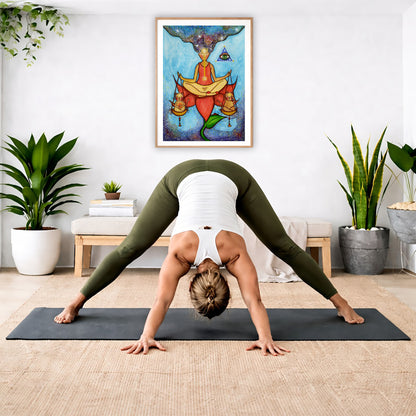Poster of a woman meditating on a lotus with a glowing third eye and holding scales balancing two cats.   The poster is in the center of the living room wall. A woman is doing a forward bend on her yoga mat. There is a padded bench below the poster with some books and a small potted plant on it. To the right and left are potted plants.
