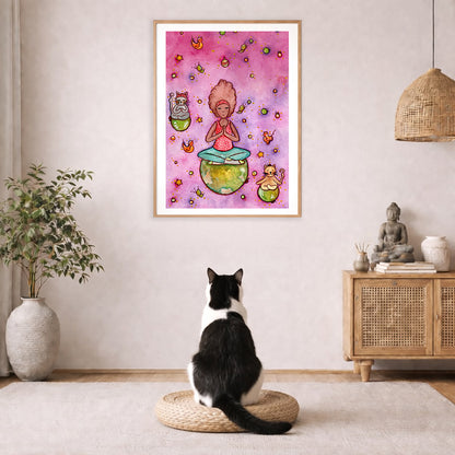 A woman and her cats meditating on the world with a pink background poster. The poster is framed and is in the center of the living room wall. A black and white cat is staring at the poster. There is a potted plant on the left side and a cabinet with a Buddha statue on it on the right side. 
