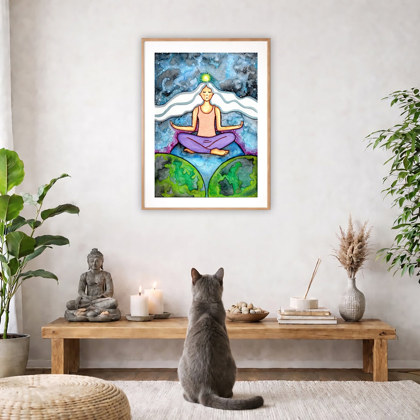 Poster of a woman meditating on three worlds with her crown chakra glowing.   The poster is in the center of the living room wall. A gray cat is facing the poster. In front of it is a coffee table with a Buddha statue and burning candle on the left and incense and an orange cat staring at the poster on the right. There is a green potted plant on both the left and right side of the coffee table.