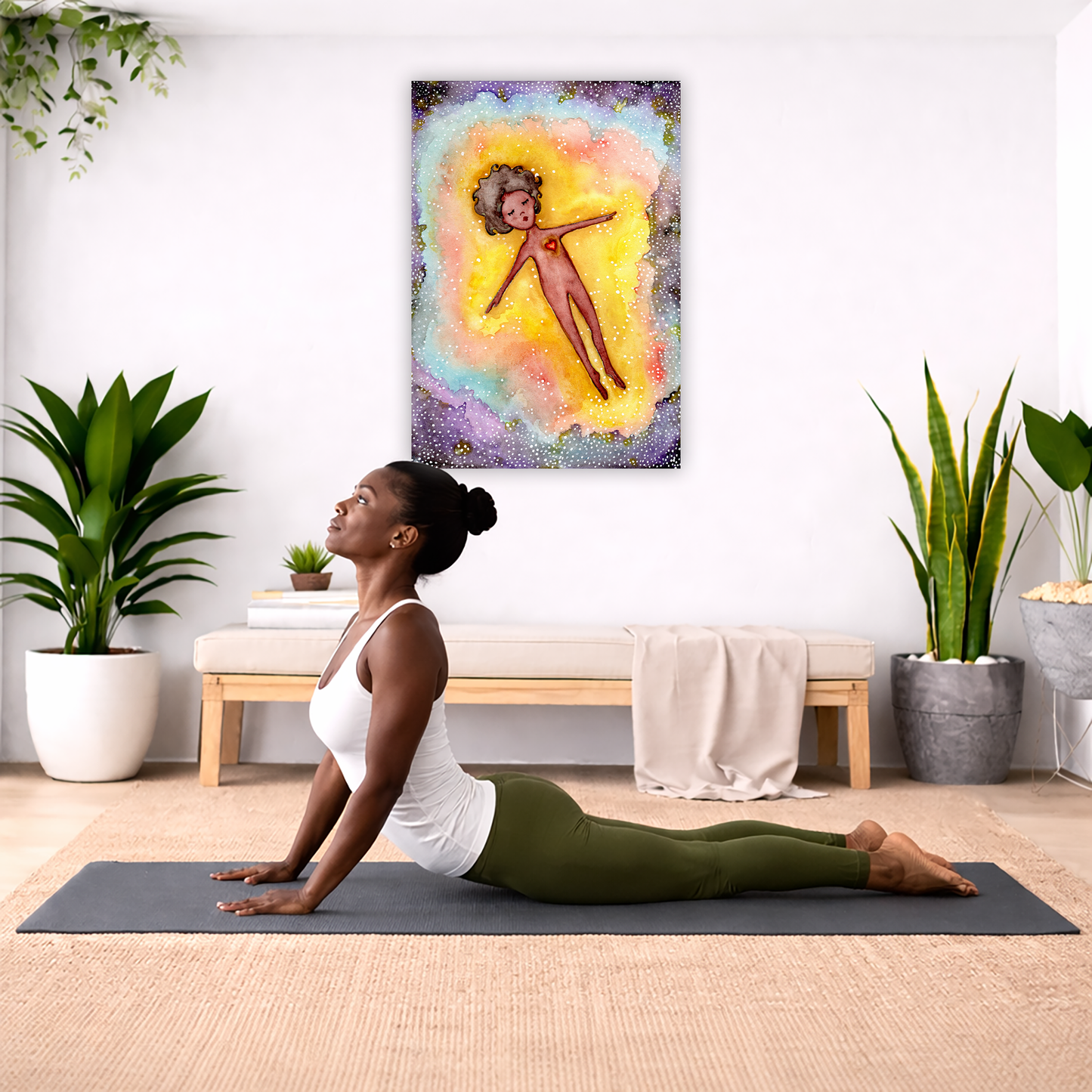 Astral body travelling in another dimension canvas poster.  The poster is hanging on the wall. A woman on her yoga mat is doing the cobra pose in front of the poster. There is a potted plant, a hanging plant and a basket of cloth material on the left side. On the right side of her is a small cabinet books and a dry plant. There is also a floor plant on the right side.
