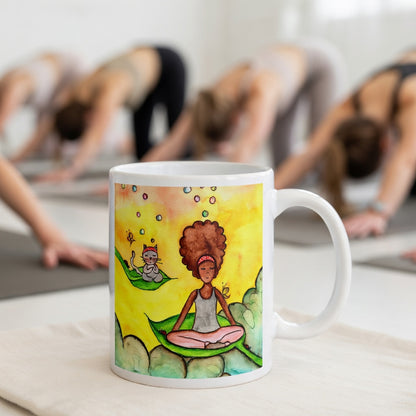Woman and cat sitting peacefully on leaves in meditation, nature-inspired mindfulness scene representing calm, balance and connection, printed on a spiritual coffee mug.  The mug is in front of a yoga class doing the downward facing dog posture.