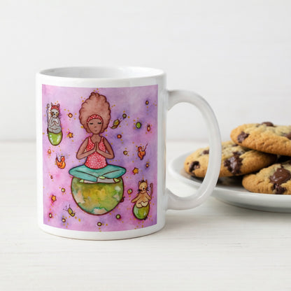 Woman and multiple cats meditating while sitting on the world, symbolizing unity, peace and global mindfulness, unique spiritual mug design.  Beside the mug is a plate of cookies.