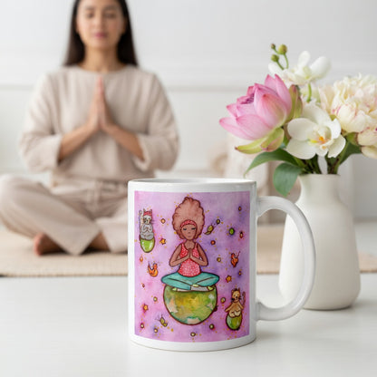 Woman and multiple cats meditating while sitting on the world, symbolizing unity, peace and global mindfulness, unique spiritual mug design.  The mug is on the floor at the bottom center of the image. In the background a woman is meditating. Beside the mug is a vase of flowers.