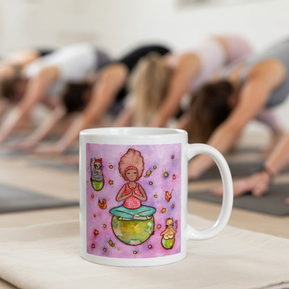 Woman and multiple cats meditating while sitting on the world, symbolizing unity, peace and global mindfulness, unique spiritual mug design.  The mug is in front of a yoga class doing the downward facing dog posture.