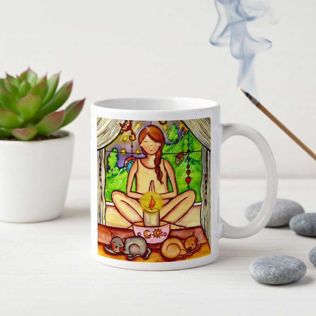 Candlelight trataka meditation design on mindfulness mug. Two cats are sleeping in front of the lady as she meditates.  The mug is on a counter. Beside the mug are meditation stones. Behind the mug is a green potted plant.