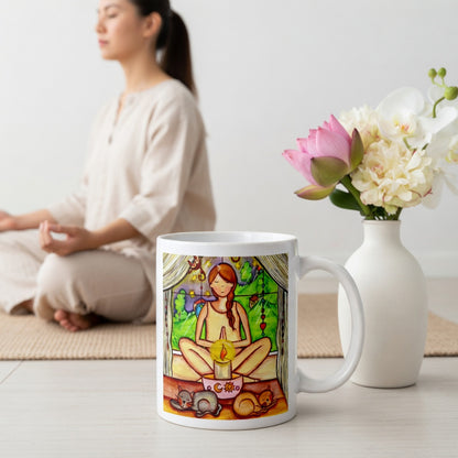 Candlelight trataka meditation design on mindfulness mug. Two cats are sleeping in front of the lady as she meditates.  The mug is on the floor at the bottom center of the image. In the background a woman is meditating. Beside the mug is a vase of flowers.