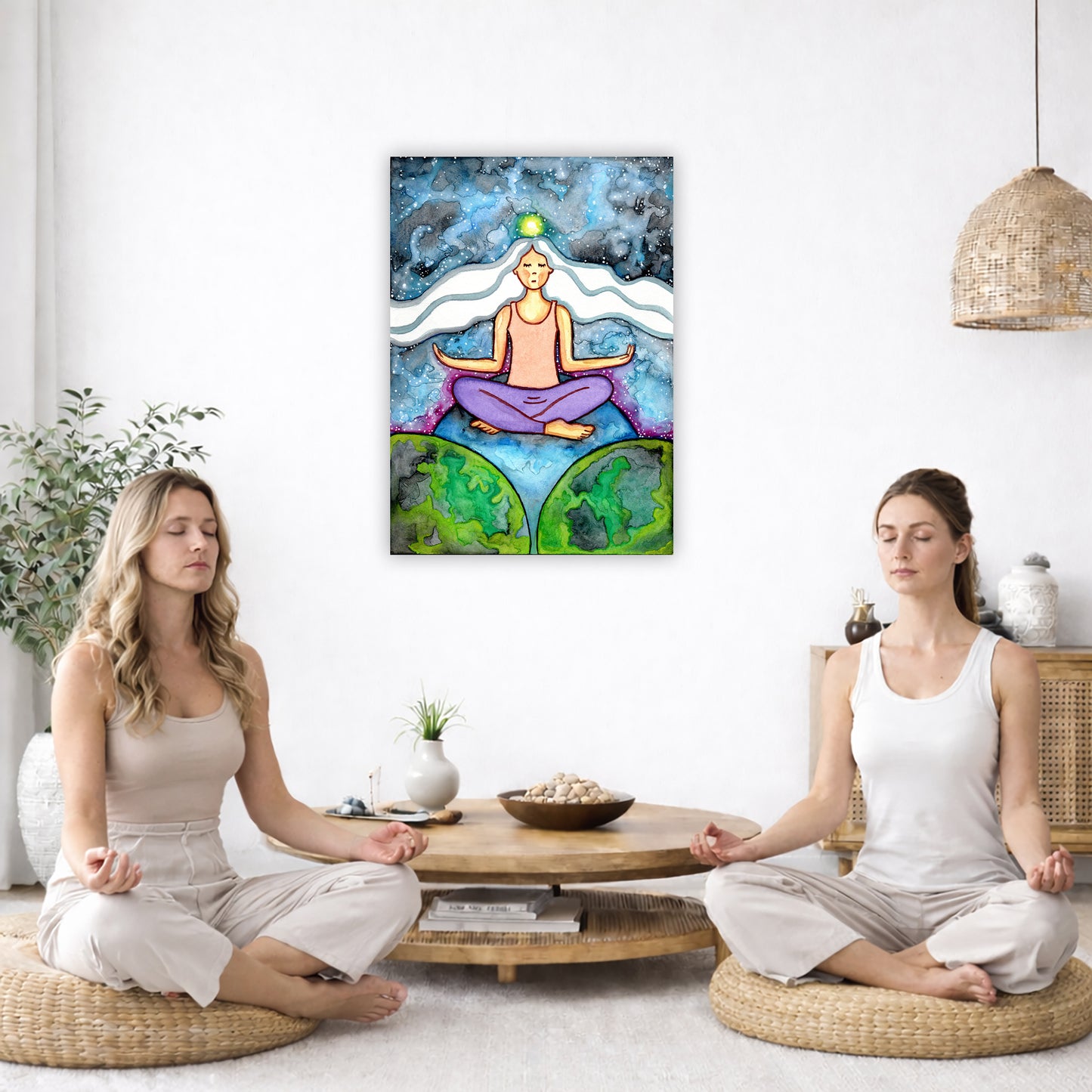 Woman with crown chakra glowing canvas poster. She is sitting on top of the world.  The poster is in the center of the living room wall. Two women are sitting on a giant pillow having a coffee. Beside them is a small tray with a pot of coffee and incense. To the left is a green floor plant and a hanging green plant. To the right of them is a green floor plant.
