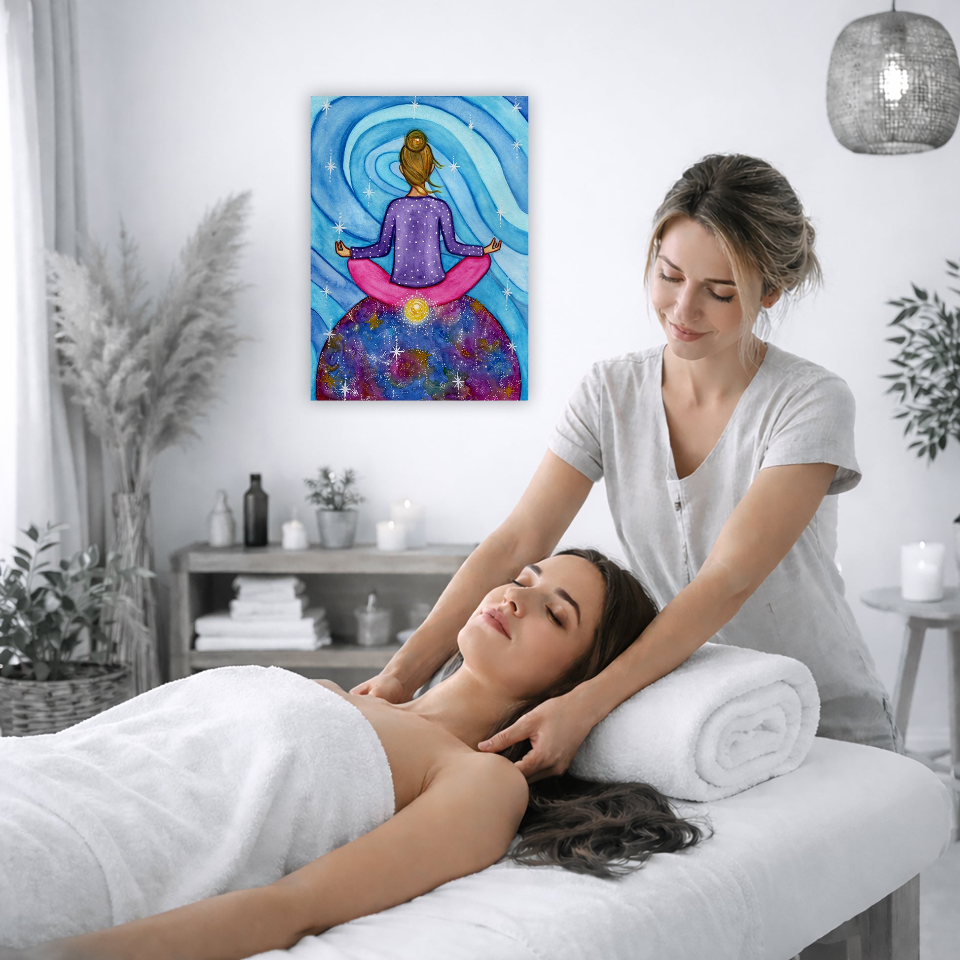 Canvas of a woman meditating with her root chakra glowing. This is a print of the original hand-painted watercolor by Brazilian artist Thaís Suizo for the LET'S MEDITATE SERIES of mediation guides.  The poster is on the wall of the office of a massage therapist. The therapist is giving her female client a massage. The client is lying face up on a massage table wearing a white towel. To the left is a window, floor plant and large vase of dry flora. A shelf is underneath the poster with candles burning.  
