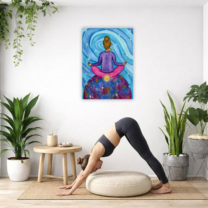 Canvas of a woman meditating with her root chakra glowing. This is a print of the original hand-painted watercolor by Brazilian artist Thaís Suizo for the LET'S MEDITATE SERIES of mediation guides.  The poster is in the center of the living room wall. Below the poster a woman is doing the yoga posture downward facing dog on a yoga mat.