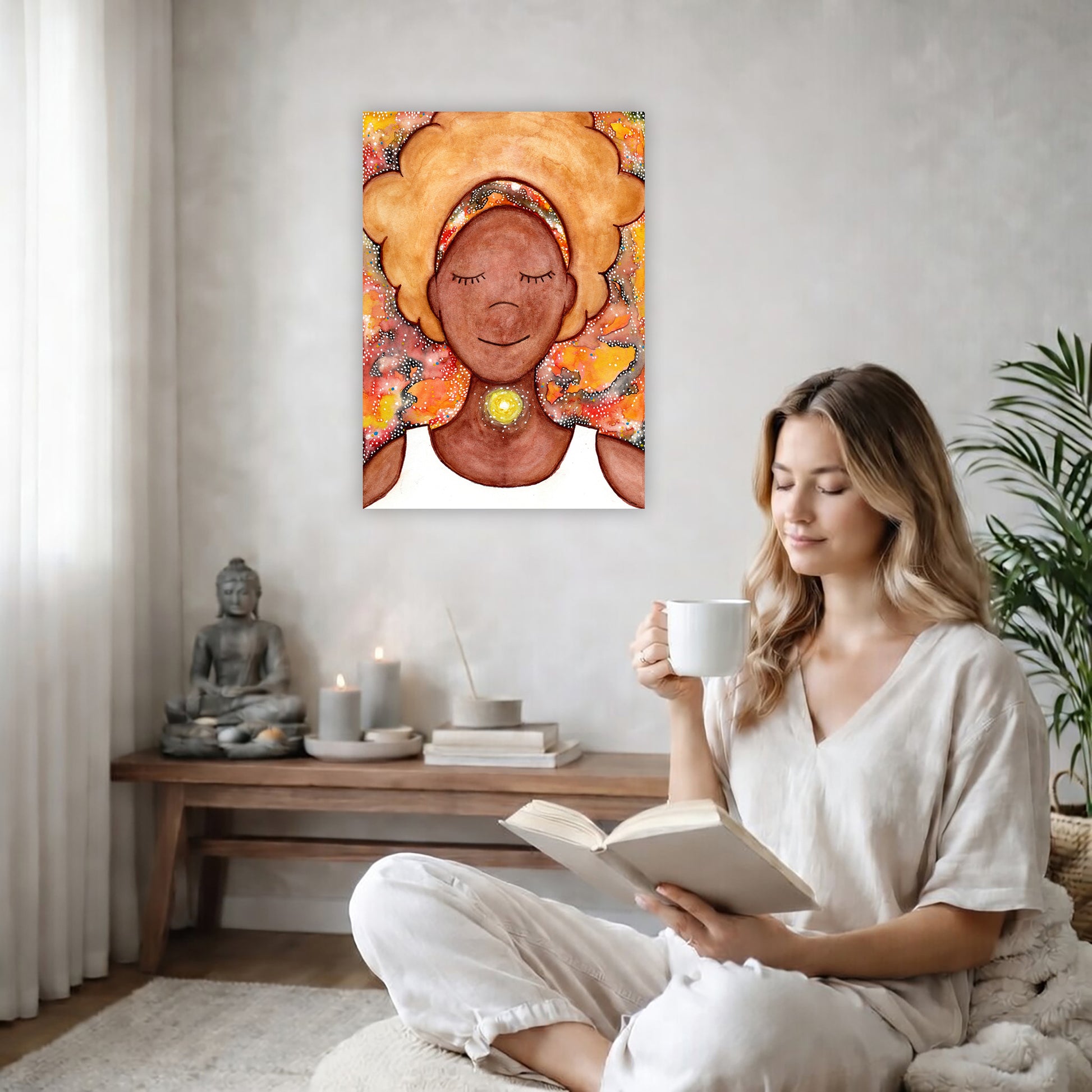 Woman's throat chakra energy glowing canvas. This is a print of the original hand-painted watercolor by Brazilian artist Thaís Suizo from the LET'S MEDITATE SERIES of mediation guides. The poster is on the back wall in the living room. There is a coffee table below the poster with burning candles and a big piece of driftwood. A woman is sitting in a wicker chair on the right side of the poster with a cup of tea reading a book. There is a potted green plant behind her.