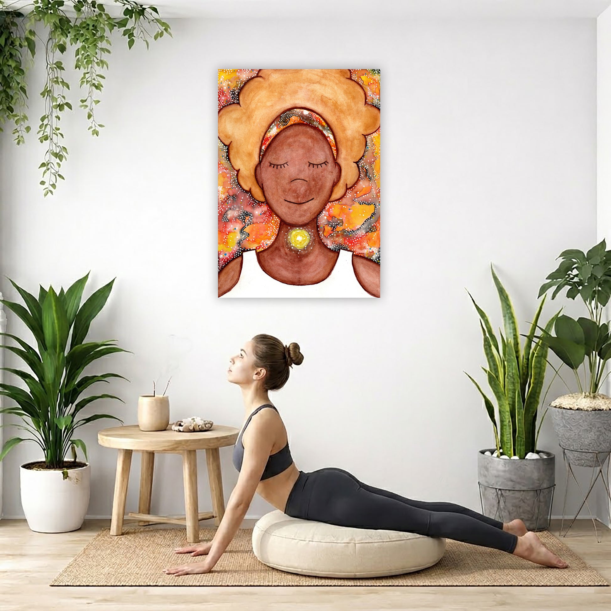 Woman's throat chakra energy glowing canvas. This is a print of the original hand-painted watercolor by Brazilian artist Thaís Suizo from the LET'S MEDITATE SERIES of mediation guides.  The poster is hanging on the wall. A woman on her yoga pillow is doing the cobra pose in front of the poster. There are several potted plants behind her including a hanging plant on the left side. There is a small table to the woman's left with incense and a bowl of shells on it.