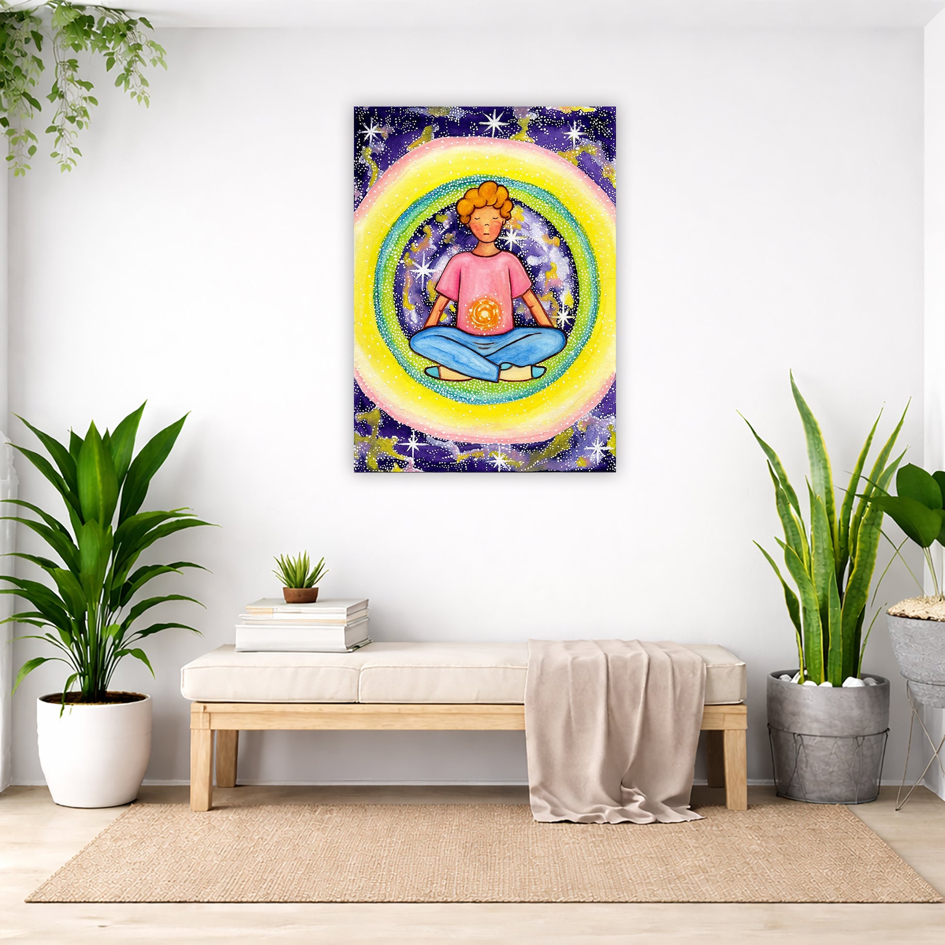 Young man meditating with his solar plexus glowing canvas. Surrounding him is his colorful aura. This is a print of the original hand-painted watercolor by artist Thaís Suizo for the LET'S MEDITATE SERIES of mediation guides. The poster is in the center of the living room wall. Below the poster is a padded bench. On the bench is a pile of books and a small green potted plant. There is a silk sheet draped over the bench. There is a green hanging plant and floor plant on the left. There are two floor plants.