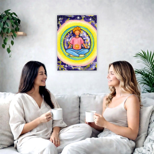 Young man meditating with his solar plexus glowing canvas. Surrounding him is his colorful aura. This is a print of the original hand-painted watercolor by artist Thaís Suizo for the LET'S MEDITATE SERIES of mediation guides. The poster is in the center of the living room wall. Two female friends are having tea, grapes and cookies on a coffee table in front of the poster. On the left there is a green potted plant and to the right there is a hanging lamp.