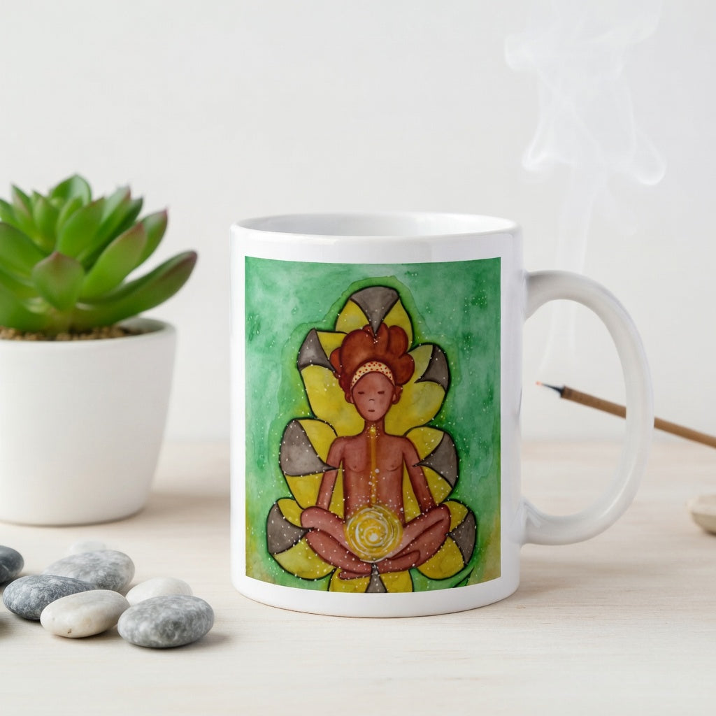 Meditating figure with glowing sacral chakra below the navel, representing creativity, passion and emotional flow, spiritual chakra artwork on a coffee mug.  The mug is on a counter. Beside the mug are meditation stones. Behind the mug is a green potted plant.