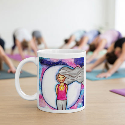Meditating person with glowing heart chakra at center of chest, symbolizing love, compassion and emotional balance, spiritual design on a mindfulness coffee mug.  The mug is in front of a yoga class doing the downward facing dog posture.