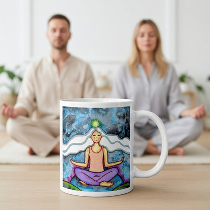 Meditating figure with glowing crown chakra at top of head, symbolizing higher consciousness and spiritual connection, chakra artwork featured on a mindfulness mug.  A large mug is at the bottom front displaying the design. There is a couple meditating in the background.