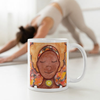 Meditating figure with glowing throat chakra, symbolizing communication, truth and self-expression, spiritual mindfulness artwork on a coffee mug.  The mug is in front of a woman doing the yoga posture downward facing dog.