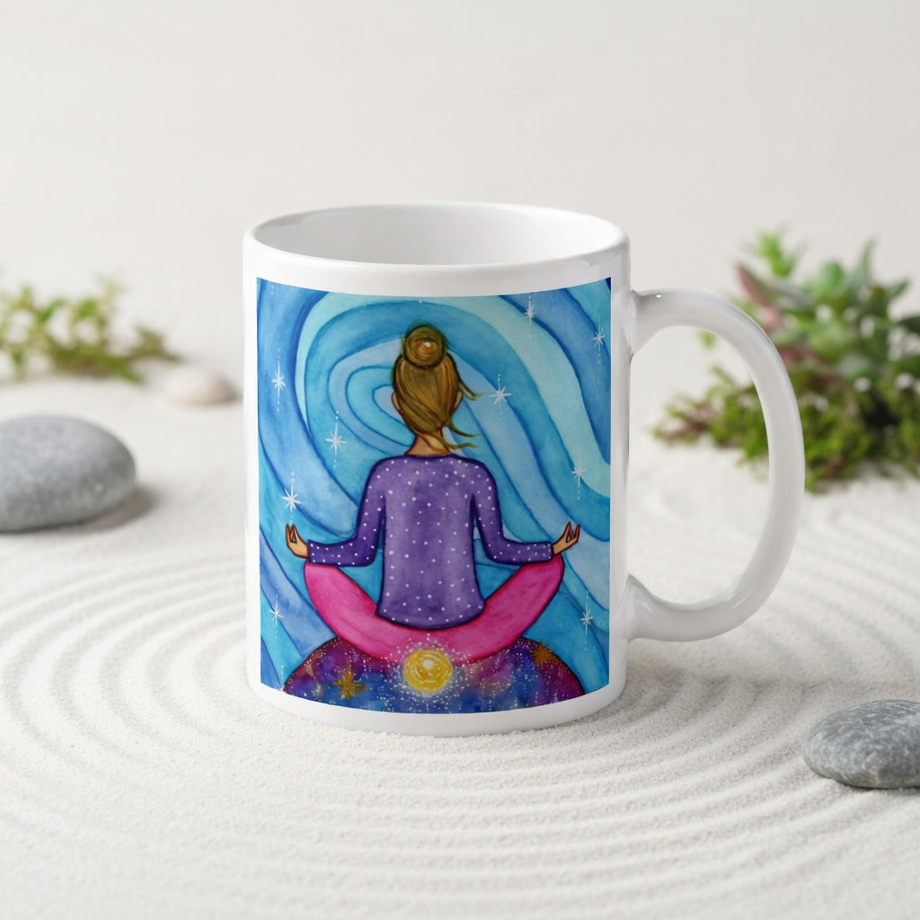 Meditating figure with glowing root chakra at base of spine, symbolizing grounding, stability and security, chakra energy artwork on a coffee mug.  The mug is in a beautifully raked zen garden with bushes and plants behind it.