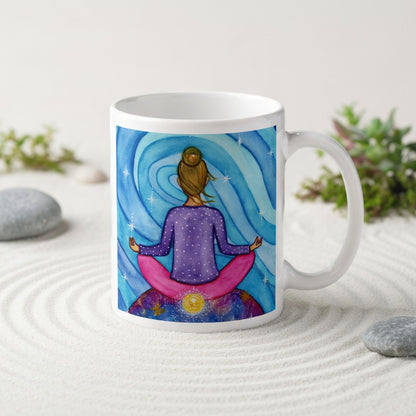 Meditating figure with glowing root chakra at base of spine, symbolizing grounding, stability and security, chakra energy artwork on a coffee mug.  The mug is in a beautifully raked zen garden with bushes and plants behind it.
